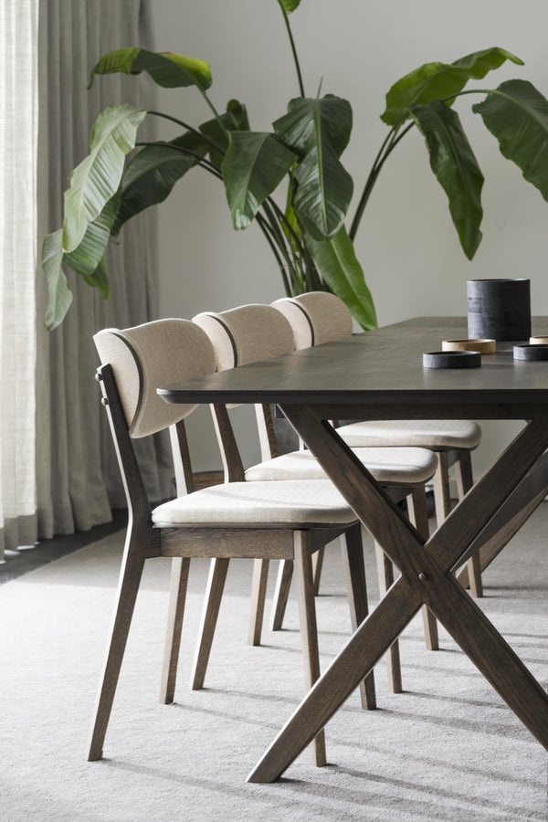 Matgrupp med bord i mörkbejsat trä med kryss-ben och stolar med beige klädsel i modern matsal