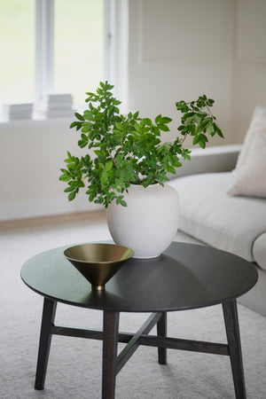 Soffbord i svartbetsad ek med rund bordsskiva, grönt glasinlägg, mässingsskål och krukväxt i vit vas