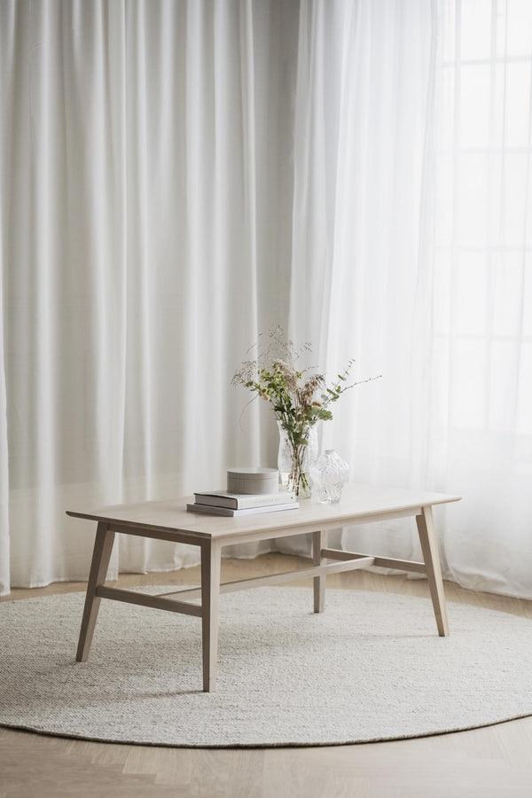 Soffbord i ljust trä med hylla, skandinavisk design, dekorerat med vas och böcker på rund matta