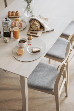 Frukostbord med stolar, dukat med bröd, kaffe, juice och ägg i ljus skandinavisk inredning