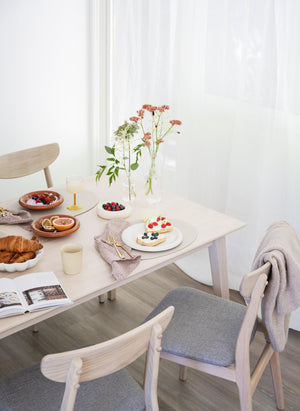 Ljust matbord med frukost, croissanter, bär och blommor i skandinavisk inredning