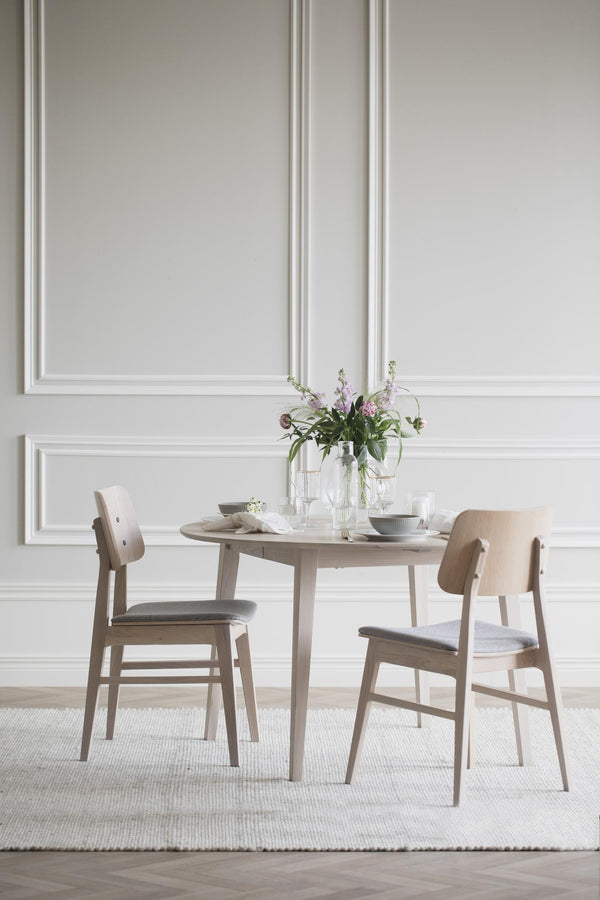 Matbord i ljust trä med stolar och elegant dukning i minimalistisk skandinavisk stil