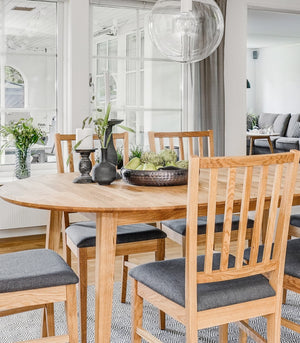 Rund matbord i ekfanér med matchande stolar med grå dynor i ljust scandinaviskt kök