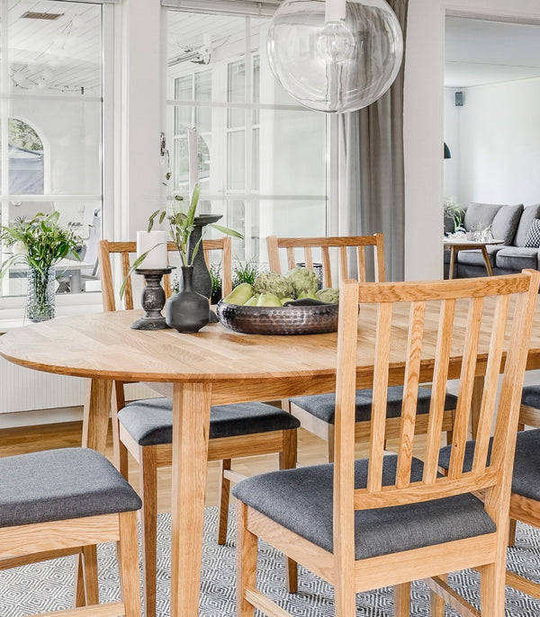Rund matbord i ekfanér med matchande stolar med grå dynor i ljust scandinaviskt kök