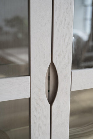 Vitlaserad träram med metalldetalj i form av mandelformad handtagslist, närbild av möbeldesign