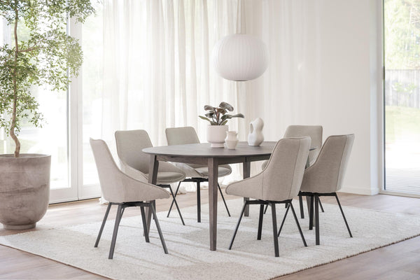 Rund matgrupp med sex beige stoppade stolar i ljus skandinavisk matsal med stora fönster