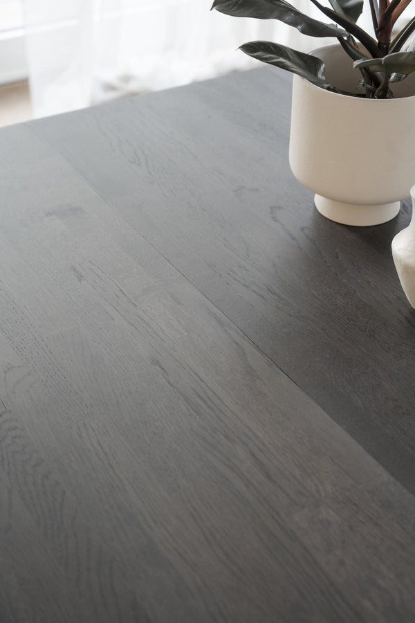 Mörkgrått laminatgolv med trästruktur och en dekorativ krukväxt i vit kruka
