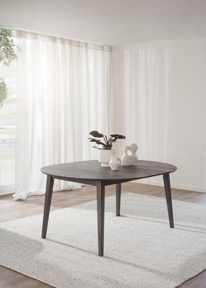 Runt matbord i mörkt trä med fyra ben, dekorerat med vita vaser och växt i ljust skandinaviskt rum