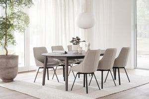 Matgrupp med ovalt bord och sex grå stolar i ljus skandinavisk matsal med stora fönster