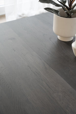 Grå laminatgolv med trästruktur och en vit kruka med växt