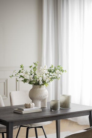 Matbord i mörkt trä med dekorativ vas, vita blommor och ljus i modern skandinavisk matsal