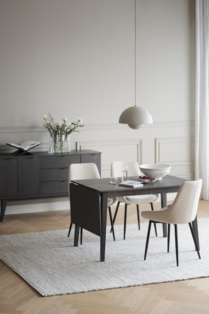 Matgrupp i mörkgrått trä med vita bouclé-stolar i modern matsal med ljus inredning