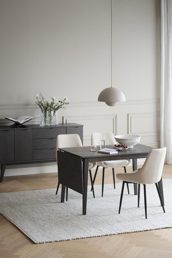 Matgrupp i mörkgrått trä med vita bouclé-stolar i modern matsal med ljus inredning