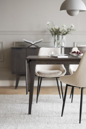 Matbord i mörkt trä med dropleaf och modern design, omgivet av cremefärgade stolar i skandinavisk stil