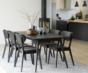 Matgrupp med svart bord och sex stolar i modern skandinavisk stil i ett ljust kök med öppen planlösning