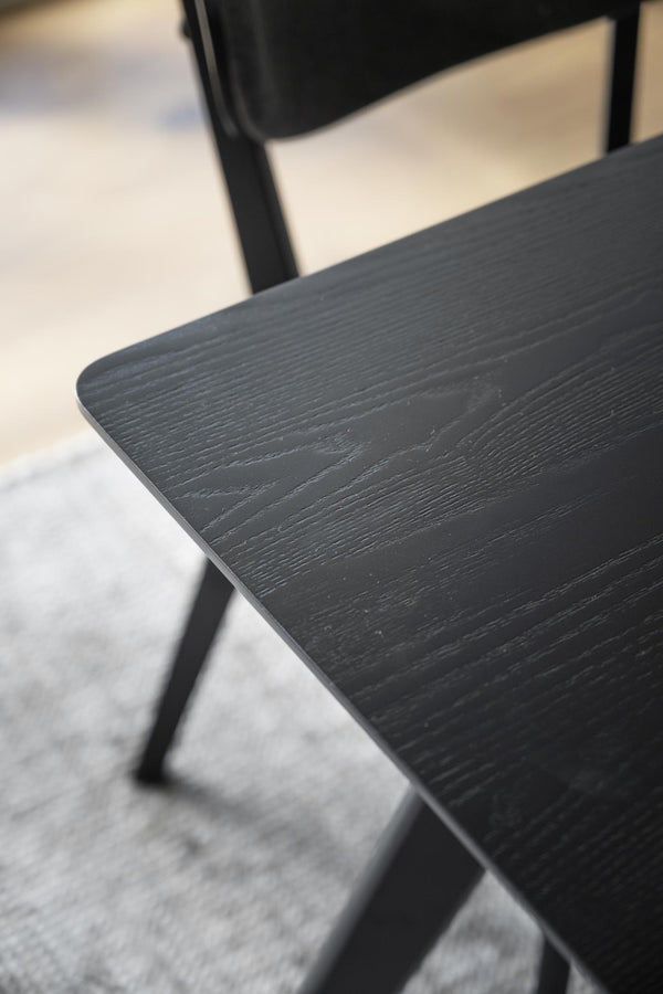 Närbild på svart träbordsskiva med synlig trästruktur och rundad kant på modern stol