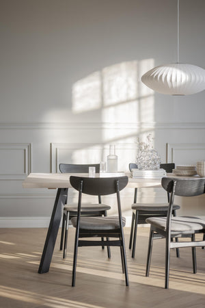 Matbord i ljust trä med svarta stolar och vit taklampa i skandinavisk design