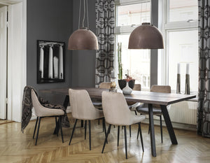 Matgrupp med bord och stolar i modern skandinavisk stil med stora taklampor och grå vägg