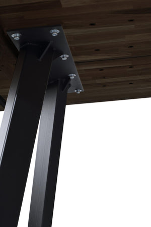 Svart metallbordsben i industriell stil monterat under träskiva med synliga skruvar