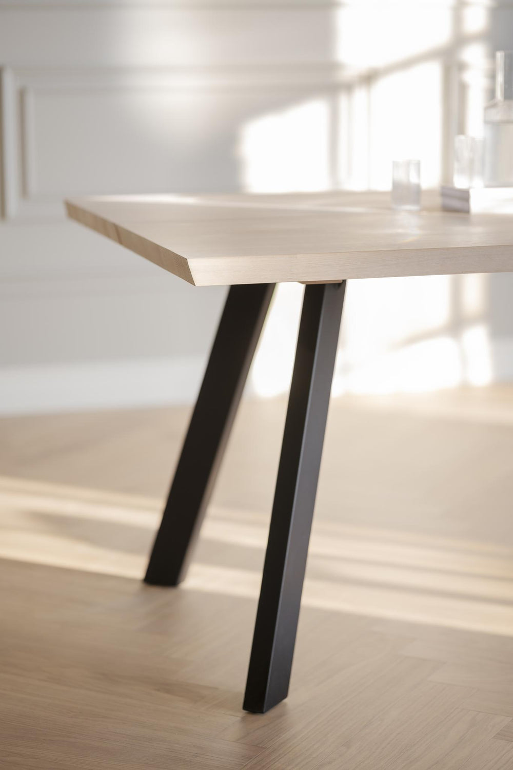 Matbord med grå träskiva och svarta snedställda ben i modern skandinavisk design
