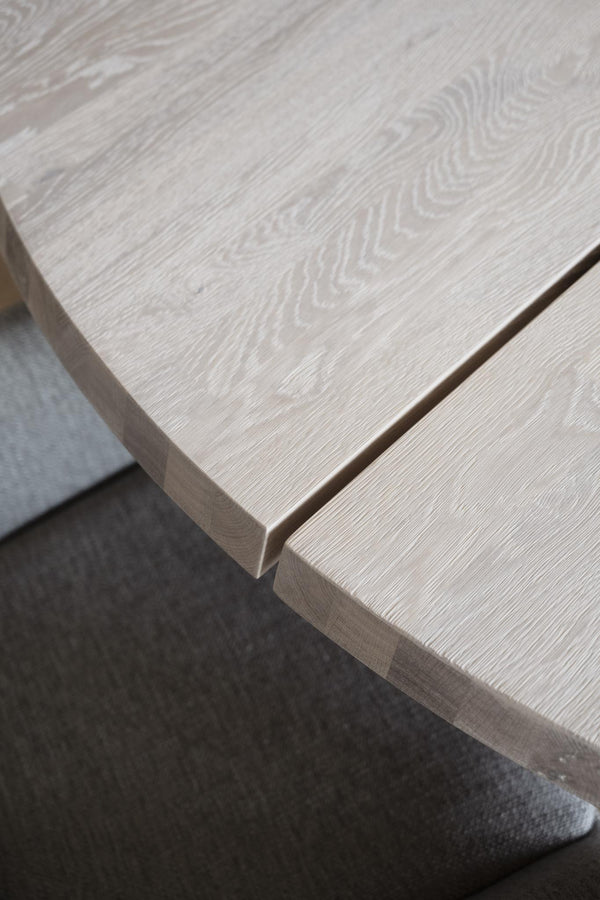 Ljust trä matbord med synlig årsringsstruktur och rundad kant, närbild av bordsskiva i ek