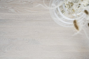 Ljust trägolv i ek med glasvas innehållande torkade blommor