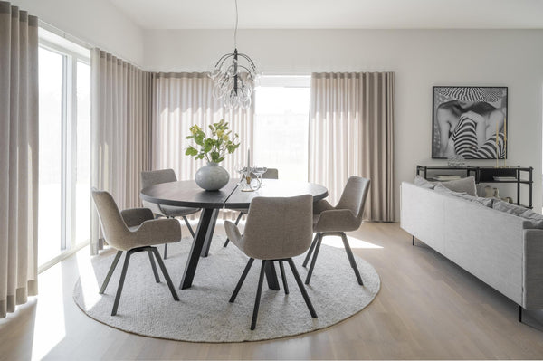 Modern matplats med runt bord, grå stolar och ljusa gardiner i skandinavisk stil