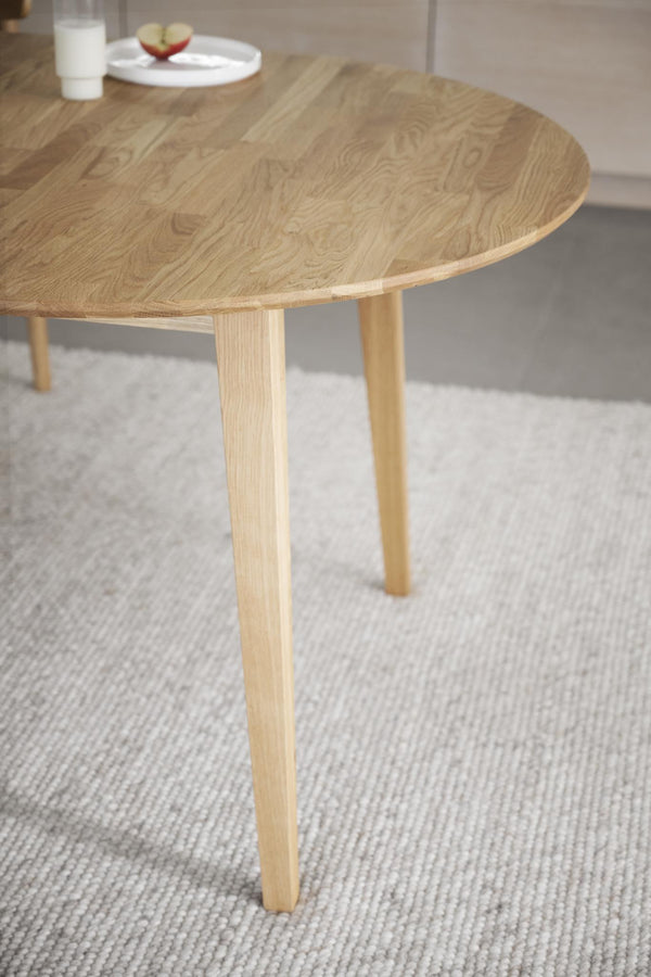 Runt soffbord i ljust trä med tre ben på ljusgrå matta i skandinavisk stil
