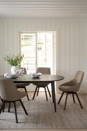 Matgrupp med ovalt bord och fyra bruna stolar i modern skandinavisk matsal med vita väggar