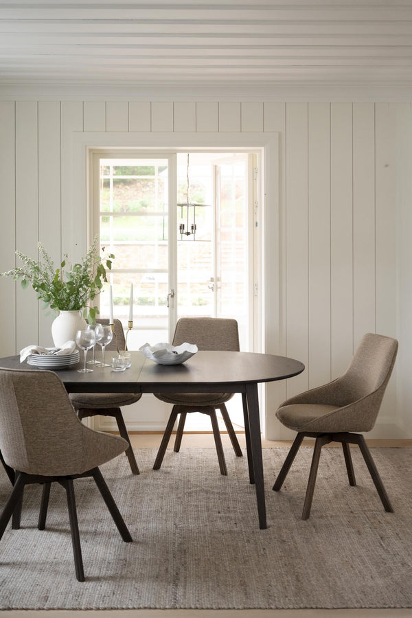 Matgrupp med ovalt bord och fyra bruna stolar i modern skandinavisk matsal med vita väggar