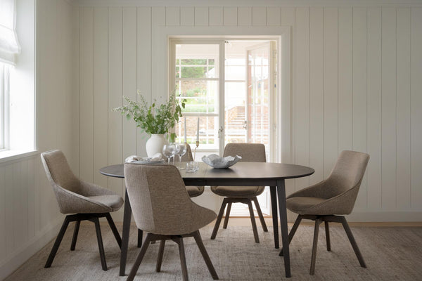 Matgrupp med runt bord i mörkt trä och fyra beige stoppade stolar i modern skandinavisk stil