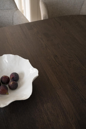 Mörkbrun parkettgolv i ek med synlig trästruktur, vit dekorativ tallrik med fikon på soffbord