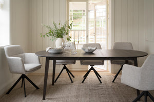 Matbord i mörkt trä med fyra grå stoppade stolar i modern skandinavisk matsal med ljusa träväggar