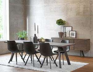 Matgrupp med grå bord och svarta stolar i modern matsal med betongvägg och träskänk