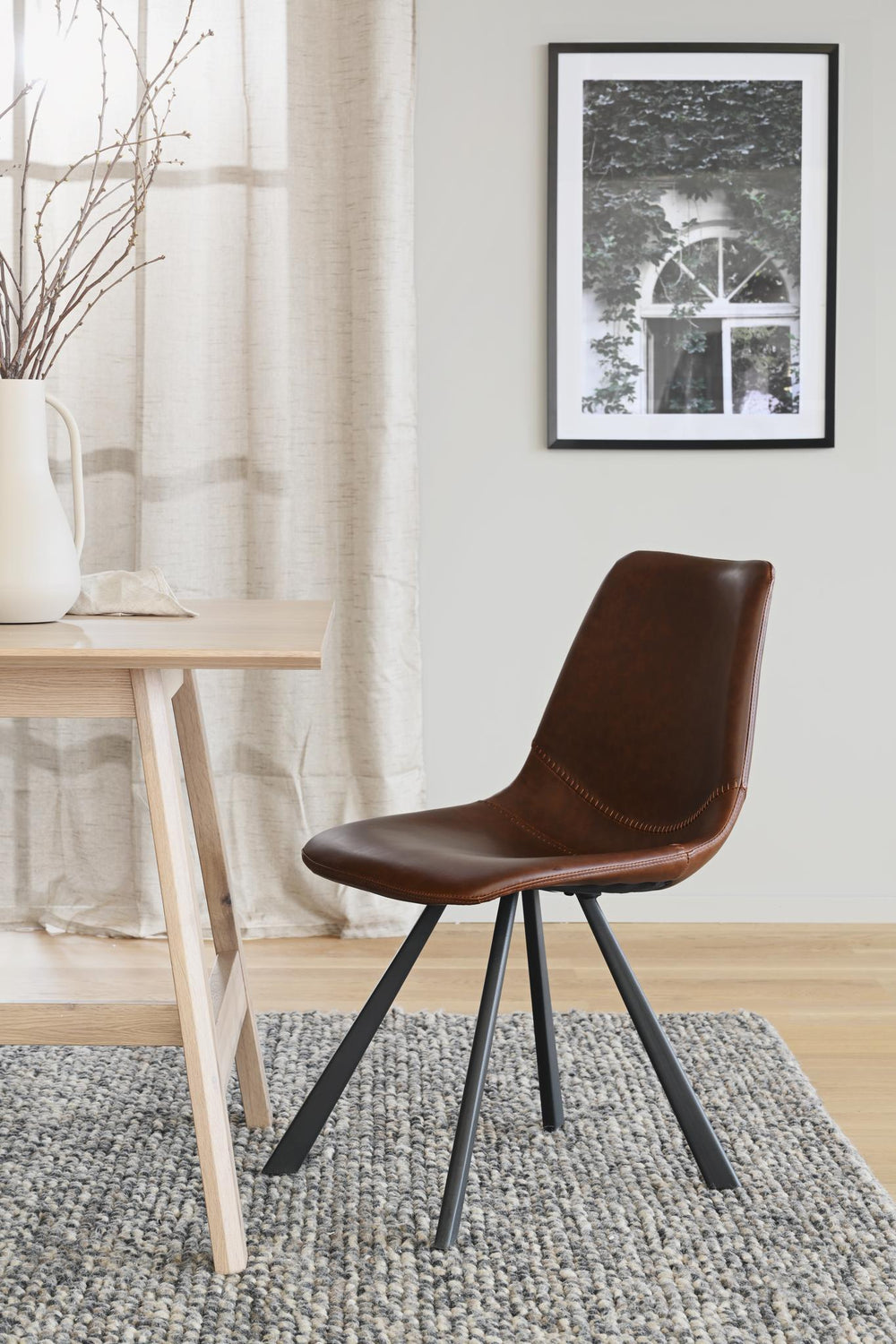 Brun läder matstol med svarta metallben i modern design, frontvy