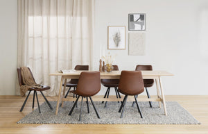 Matgrupp med ljust trähbord och sex bruna stolar i modern skandinavisk matsal med tavlor på väggen