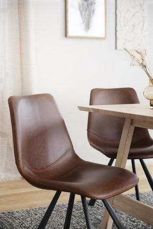 Bruna läder matstolar med svarta ben vid ljust trä matbord i modern skandinavisk matsal