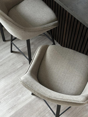 Stol med beige tyg och svarta metallben vid bord med räfflad design, modern skandinavisk inredning