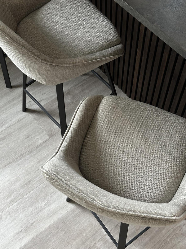 Stol med beige tyg och svarta metallben vid bord med räfflad design, modern skandinavisk inredning