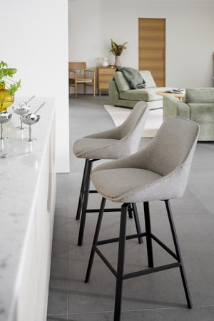 Gråa barstolar med svarta ben vid vit barkdisk i modernt vardagsrum med naturliga toner