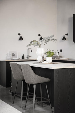 Modernt kök med marmorbänkskiva, gråa barstolar och svarta vägglampar i skandinavisk design