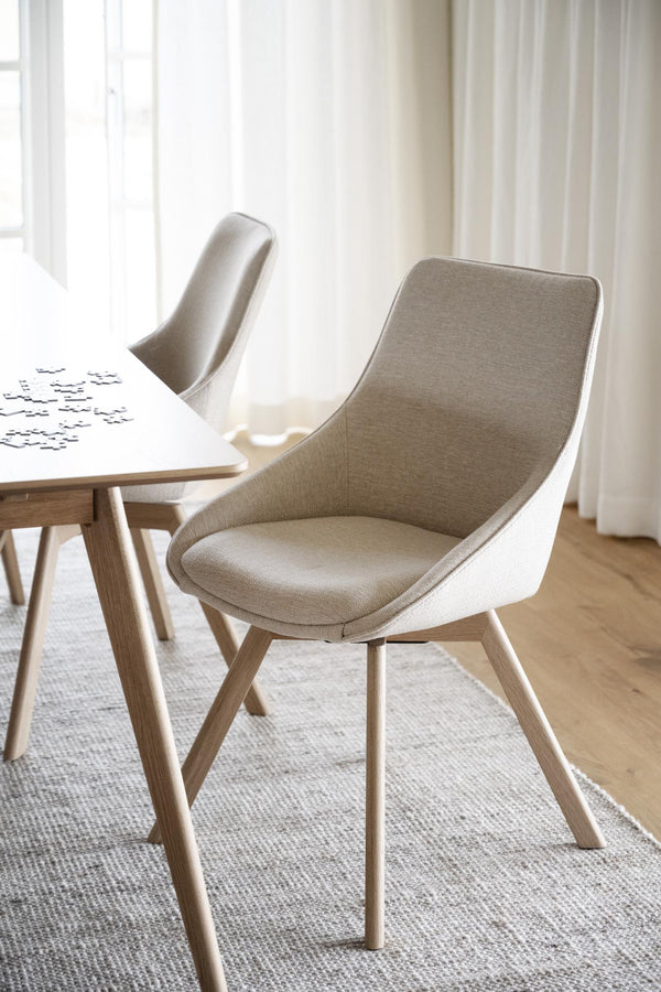 Moderna matstolar med beige tyg och ljusa träben vid matbord i skandinavisk stil