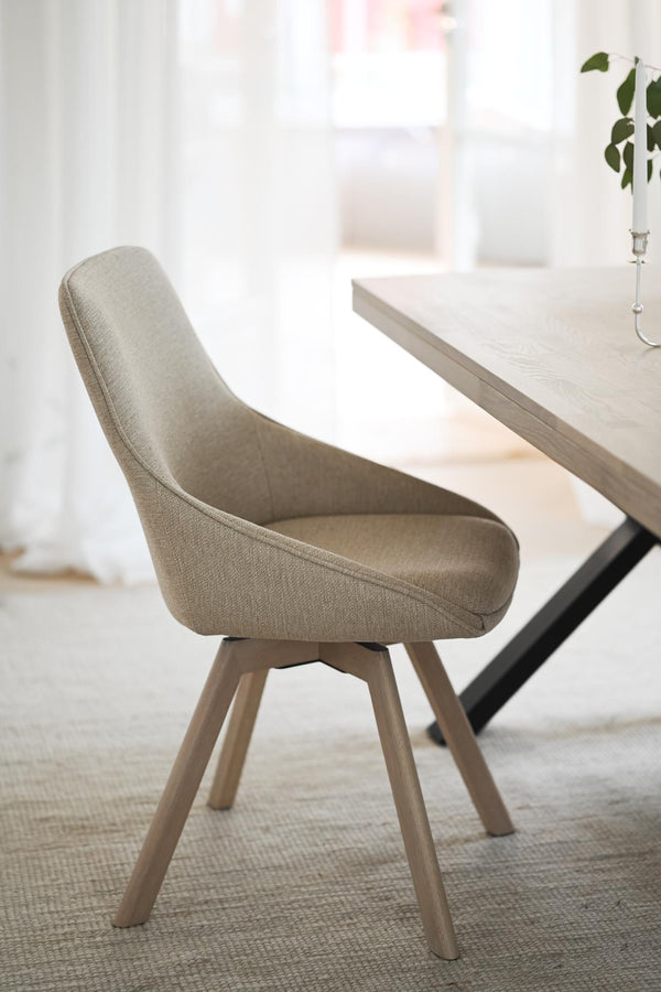 Beige stoppad matstol med träben vid matbord i ljus modern matsal