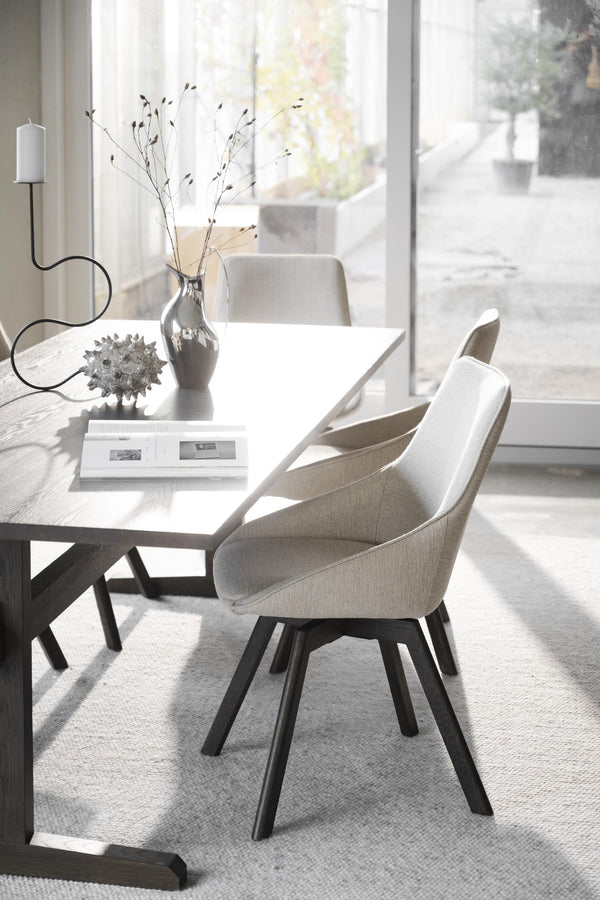 Moderna matstolar med beige tyg och svarta ben vid matbord i ljust skandinaviskt hem