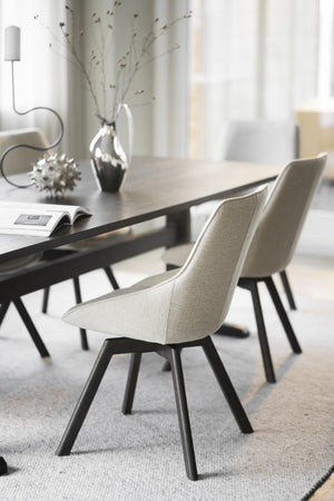 Beige matstol med svarta ben vid modern matbordsbord i skandinavisk matsal med minimalistisk inredning