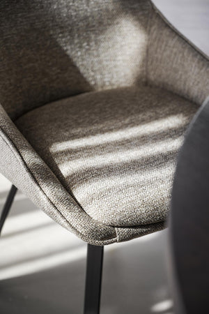 Närbild på grå stoppad stol med tyg i schackrutigt mönster och svarta ben