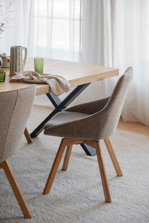 Matsalsstol i grå tyg med träben vid matbord i ljus inredning