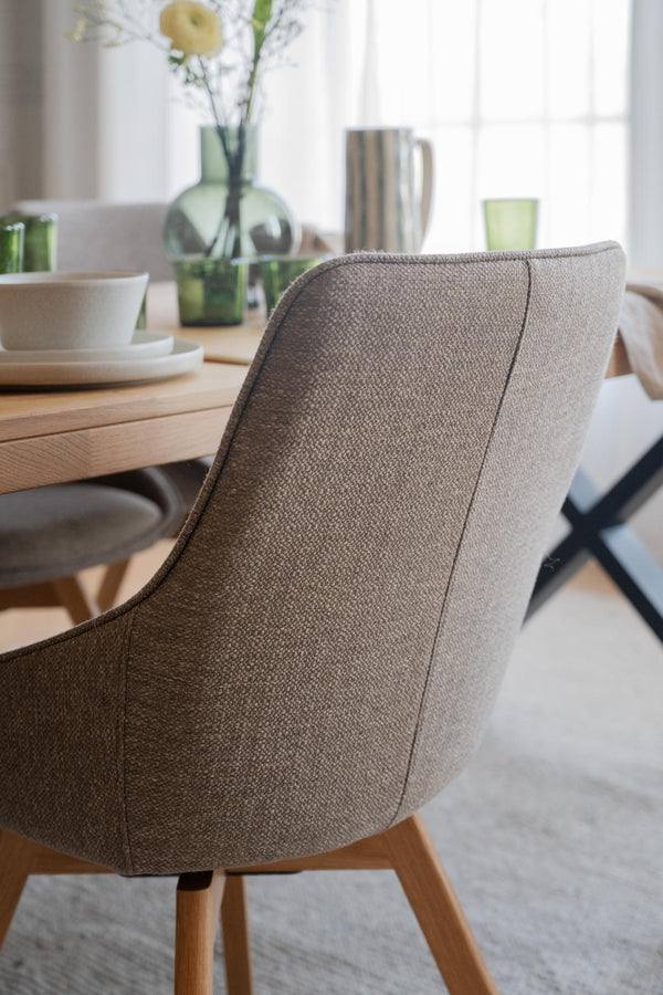 Beige matstol med träben vid matbord i skandinavisk design med gröna glasdetaljer