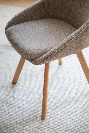 Brun stol med träben och stoppad sits i tyg på ljus matta, modern skandinavisk design