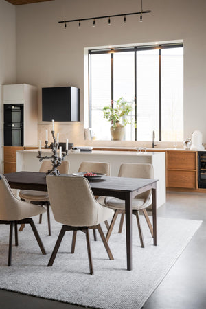 Modern matplats med grå stolar och massivt matbord framför öppet kök med trädetaljer och stora fönster